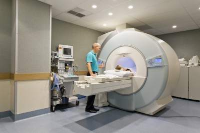 MRI machine with patient going inside and doctor watching